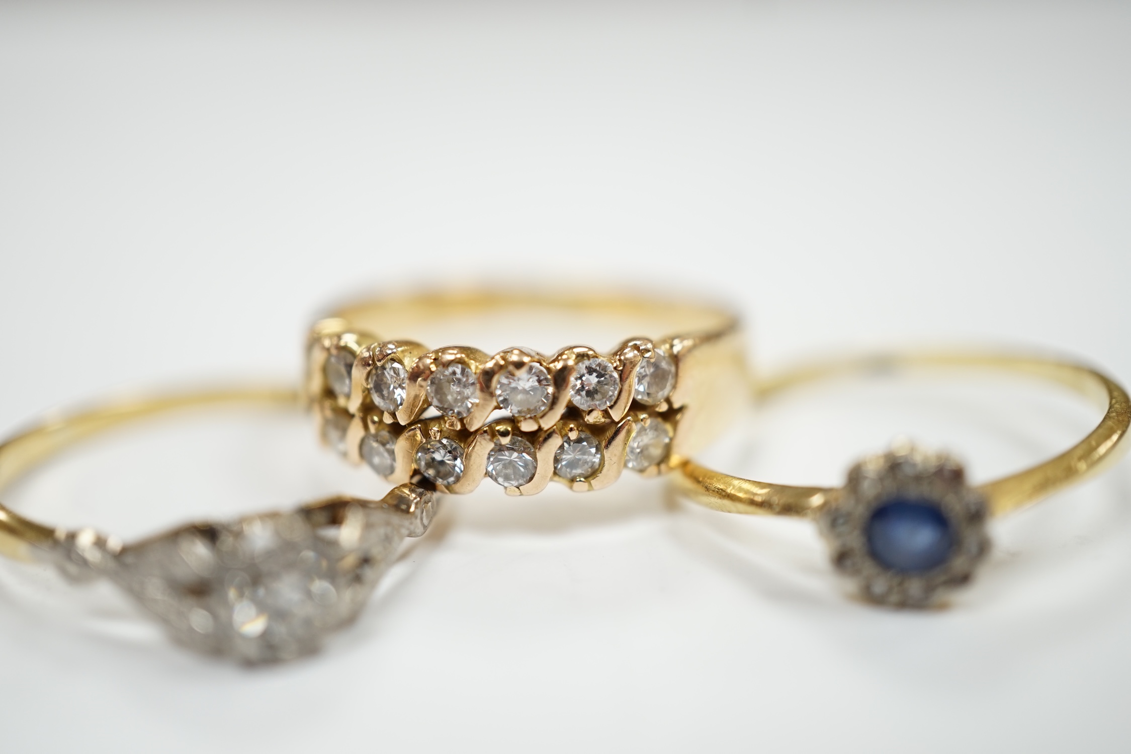 Three assorted yellow metal and gem set rings including an 18ct, plat and illusion set solitaire diamond ring, size Q, gross weight 8.1 grams.